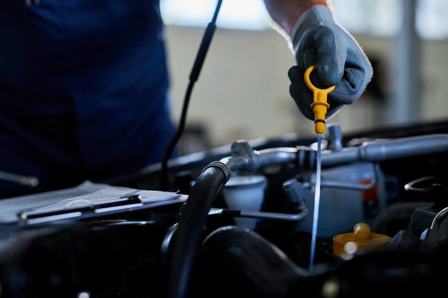 Professional oil change service in Kuwait with expert mechanic checking engine oil.